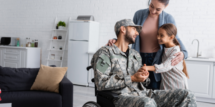 A military member in a wheelchair with his family in a kitchen/living room.